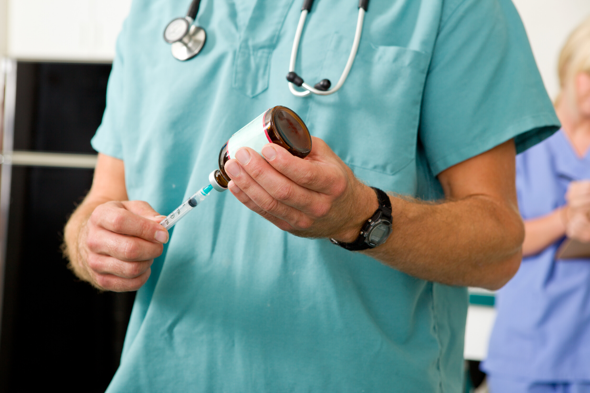 veterinarian drawing up vaccines out of a brown glass bottle